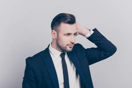 Portrait of half turned stunning ideal boss touching his hair looking to the side over grey...