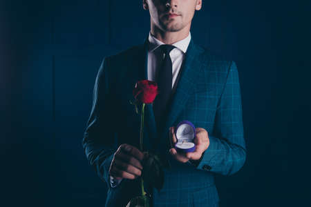 Close up half face portrait of man in formal wear, holding in one hand box with engagement ring and...