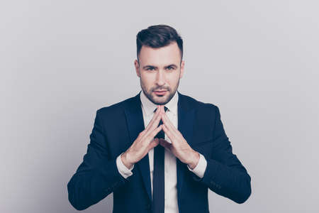 Portrait of stunning boss in blue jacket folded finger to finger  with serious expression looking at...