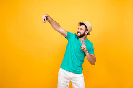 Hey what's up? Happy funky cheerful joyful man clothed in casual outfit taking a self portrait on his new smartphone and showing two fingers, copyspaceの写真素材