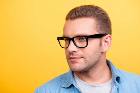Close up portrait of bearded man in glasses with serious expression looking to the side over yellow backgroundの写真素材