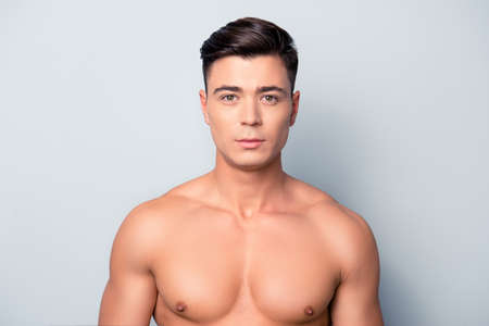 Portrait of confident concentrated handsome muscular with perfect ideal skin shaven guy, isolated on grey backgroundの写真素材