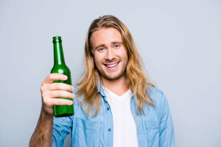 Portrait of happy, smiling guy holding a bottle of beer, ready to cheer on favorite team, watch...