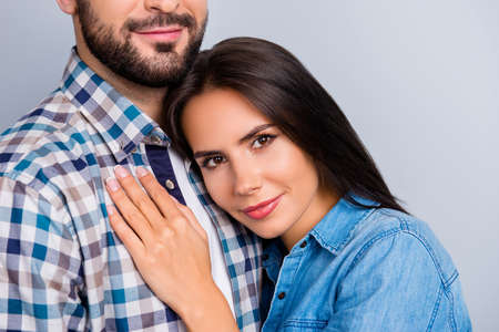 Close up cropped portrait of beautiful, pretty lovely, joyful, dreamy girl enjoying embrace with her bearded boyfriend, put head on his chest, couple in shirt over grey backgroundの写真素材