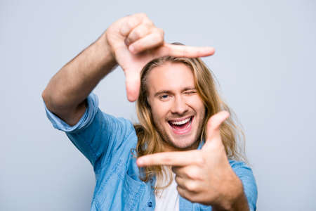 Closeup of young, attractive, happy, creative, cheerful man making frame with fingers, looking at...