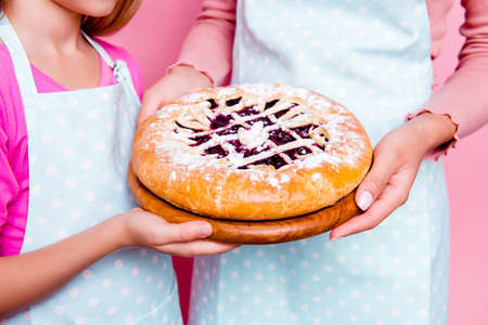Close up portrait of tasty pie with strawberry, cherry filling  in hands of mother and daughter in...