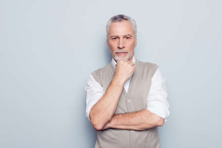 Close up portrait of qualified serious strict pensive clever head on big company thinking over new start-up in his business rolled-up sleeves white shirt beige waistcoat isolated on gray backgroundの写真素材