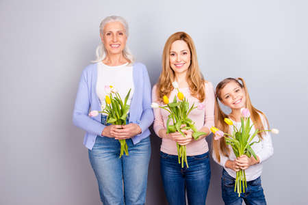 Bloom blossom event weekend vacation relax rest day-off femininity motherhood maternity concept. Cheerful joyful cute tender charming three family members holding tulips isolated on gray backgroundの写真素材