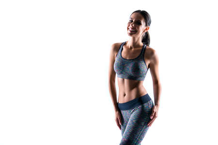 Result of trainings is right nutrition and being on diet. Attractive sportive taut stunning wonderful slim woman's body she is wearing top and sport pants, isolated on white background copyspaceの写真素材