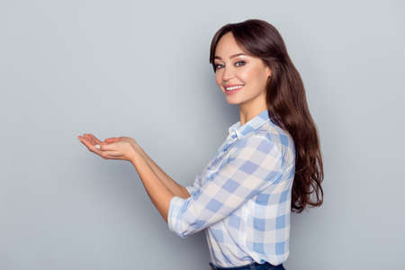 Advertisement concept. Portrait of gorgeous, cute, perfect, cheerful, attractive, caucasian woman  showing in two hands copy space on her palms on grey background, presenting new productの写真素材