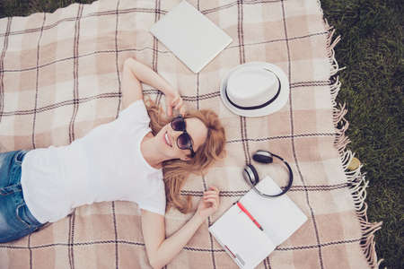Above overhead top view photo of excited cheerful joyful pretty blonde inspired woman lying on plaid grass and dreaming fantasizing, looking on the skyの写真素材