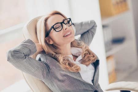 Close up portrait of joyful smiling happy cheerful charming beautiful wearing glasses and grey suit, she completed all tasks and now is having a restの写真素材