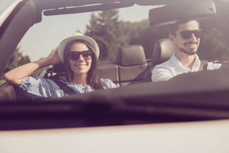 Married family, friendship, trip, relax, chill, escape, speed ride, valentine. Closeup of well dressed brunet driver in eyewear, femenine gorgeous cute brunette lady on way to sweet honeymoonの写真素材