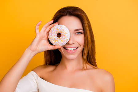 Diet, calories, healthcare, willpower, body care, concept, close up portrait of charming, cute girl with naked shoulders, holding sweet donut near eye, laughing, so playful and hungry, sexy and hotの写真素材