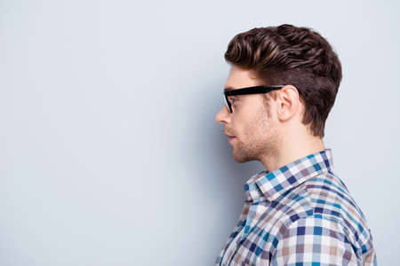 Advertisement concept. Profile of smart, clever guy in glasses  looking at copy space over grey backgroundの写真素材