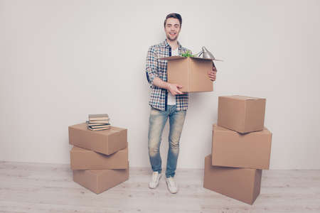 Full-length full-size portrait of glad satisfied rejoicing handsome young man carrying box with...