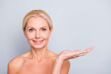 Portrait with empty place of charming, attractive, nude woman with smooth, soft, perfect, ideal, pure, fresh skin holding copy space on her palmの写真素材