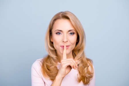 Portrait of pretty, charming, mysterious, sexy, attractive woman holding forefinger on mouth, asking to keep silenceの写真素材