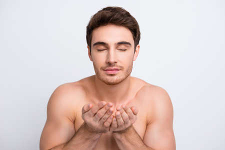 Close up portrait of delightful confident attractive handsome muscular masculine guy is going to wash clean his face isolated on gray backgroundの写真素材