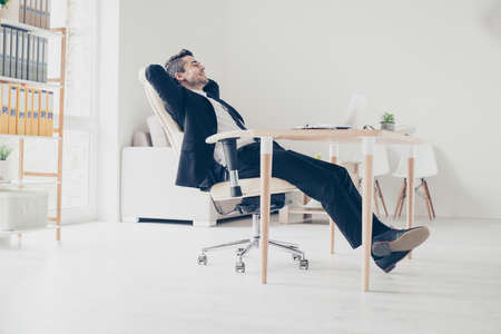 Side profile view full-length full-size portrait of excited cheerful delightful thoughtful careless leader manager relaxing on armchairの写真素材
