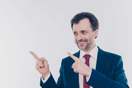 Portrait of excited cheerful satisfied delightful emotional expert experienced qualified freelancer demonstrating copyspace over shoulder isolated on gray backgroundの写真素材