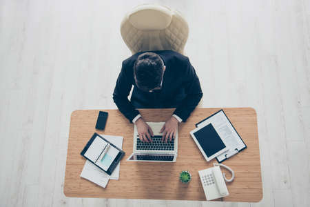 Top view photo of busy confident concentrated marketer entrepreneur typing email to colleagues clients white wooden floor backgroundの写真素材