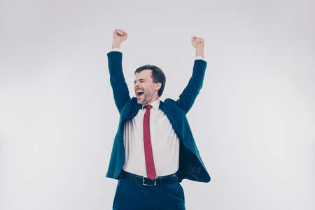 Portrait of excited surprised cheerful delightful with red tie white shirt banker raising hands up isolated on gray backgroundの写真素材