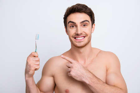 muscular male model, gesture effective teeth brush with forefinger , isolated on grey backgroundの写真素材
