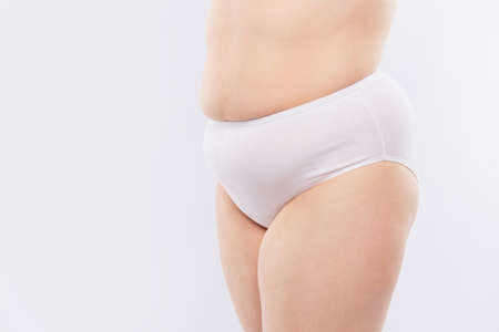 Cropped close up photo of woman's lower fatty body wearing white underpants, isolated on white background, copy-spaceの写真素材