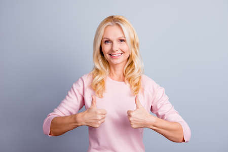 Portrait of cute dream dreamy lovely beautiful confident satisfied middle aged woman demonstrating thumb-up isolated on gray backgroundの写真素材