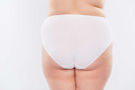 Rear behind cropped view photo of fatty cellulite shapeless chubby woman's butt wearing big-size white underlinen, isolated on white backgroundの写真素材