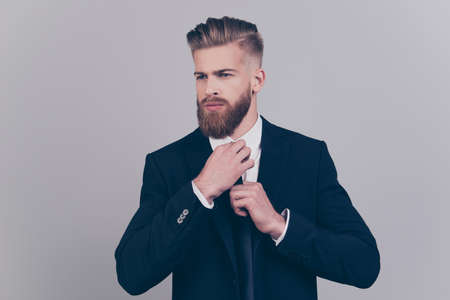 Portrait of confident leader serious handsome attractive luxurious wealthy groomed modern pondering minded self-assured intelligent person people banker  correcting neck-tie isolated gray backgroundの写真素材