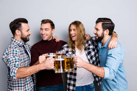 Tourism trip travel lager bock draught ethnicity diversity restaurant. Four cheerful excited friends, checkered casual shirt clinking pints of beer, hugging isolated on gray backgroundの写真素材