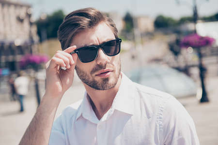 Close up portrait of handsome attractive smart stylish serious concentrated thinking focused pensive pondering with modern hairdo financier banker model fixing correcting eyewear city on backgroundの写真素材
