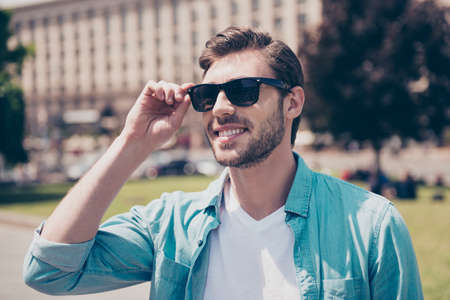 Portrait of handsome careless cheerful carefree delightful feeling good man wearing casual cozy comfortable outfit clothes touching correcting fixing glasses, sunshine, city, town, lifestyleの写真素材