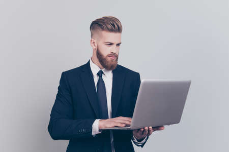 Portrait of serious focused thinking pondering pensive planning learning financier lawyer using digital netbook isolated on gray backgroundの写真素材