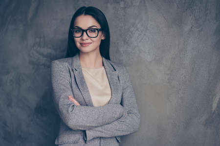 Close up portrait of clever intelligent attractive pondering beautiful executive boss wearing gray classic elegant jacket standing with folded hands isolated on concrete background copy-spaceの写真素材