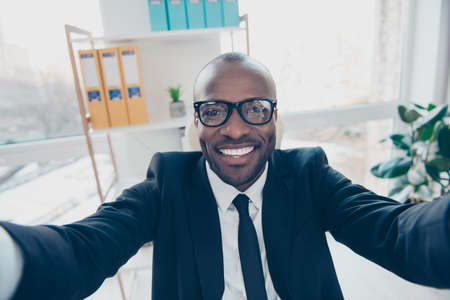 Close up self portrait of stylish, cheerful, attractive man shooting selfie in two hands, smiling at...