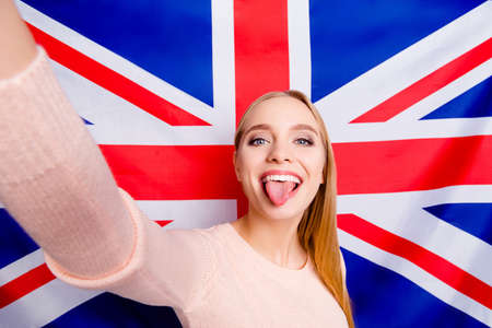 International europe style stylish people careless restless lifestyle leisure concept. Close up portrait of excited cheerful comic joking blogger demonstrating tongue taking making selfieの写真素材