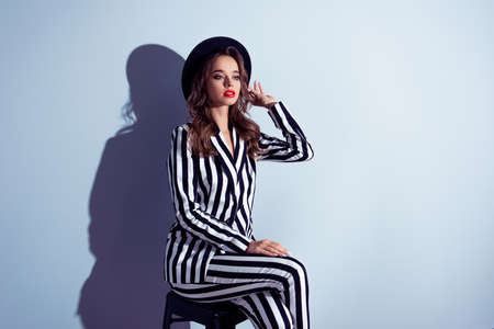 Half-turned portrait of graceful stunning exquisite posh self-assured famous popular wealthy luxurious classy lady diva with long curly hair dressed in catchy clothes isolated on gray backgroundの写真素材