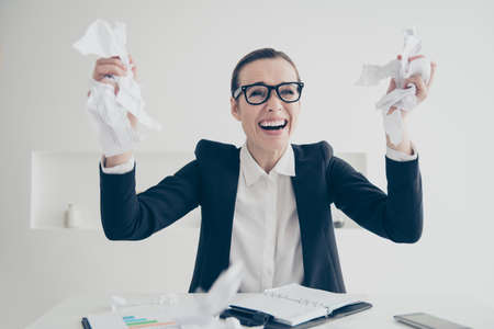 Portrait of beautiful, attractive manager in glasses with crumpled papers in hands and nervous, frustrated, disappointed expression sitting at desktop in work place, stationの写真素材