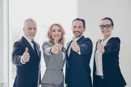 Portrait of attractive, cheerful, confident, stylish business persons standing in work place, station showing thumb up, like symbol, looking at camera, teambuilding, teamwork conceptの写真素材