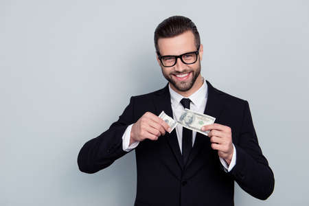 Collar modern cashback budget reduce price less interest cost customer concept. Portrait of confident smart handsome salesman holding two halves on banknote isolated on gray backgroundの写真素材