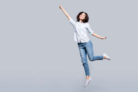 Full length, fullbody portrait of pretty, charming, stylish, modern girl in denim outfit jumping in...