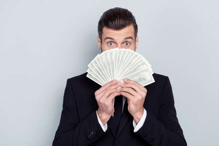 100 buy transfer stock shares people success luck concept. Close up portrait of surprised excited amazed wondered glad financier economist hiding face behind money in hands isolated on gray backgroundの写真素材
