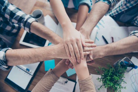 We are strong together! Concept of trust support collaboration. Top above overhead view photo of symbolic tower made of people's put hands over desktop with notesの写真素材