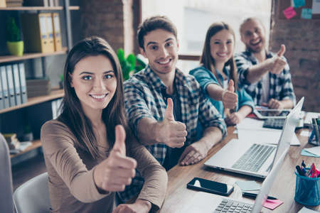 Portrait of four young, happy, cheerful community, four workers in the office, sitting at desk,...