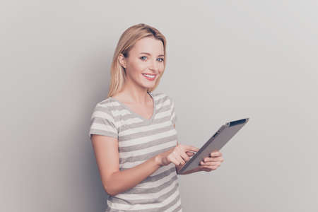 Portrait of pretty, charming, cute girl touching touchscreen of tablet with finger, looking at...
