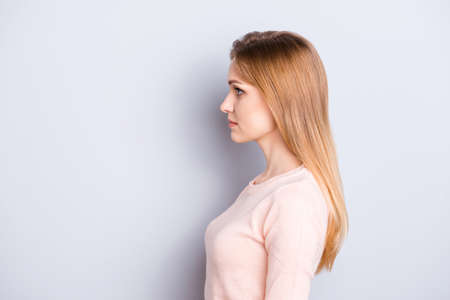 Half-faced view portrait of confident focused charming tender lovely gorgeous pretty with good face featured woman looking aside wearing peachy light pink pullover jumper isolated on gray backgroundの写真素材