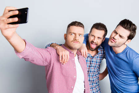 Portrait of cheerful, positive, cool, crazy, funky, childish, modern guys shooting selfie on smart...